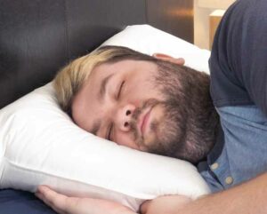 Helix Down & Feather Pillow A man sleeps on his side on the Helix Down & Feather Pillow