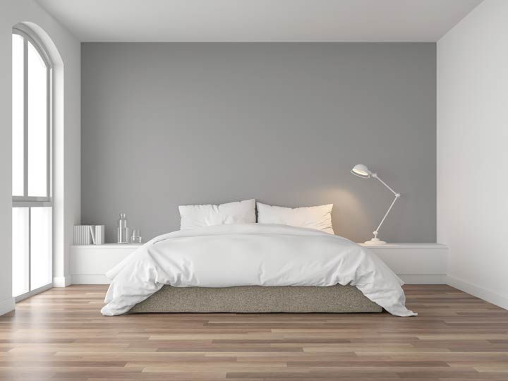 A wide shot of a minimalist bed set with white comforter and white pillows