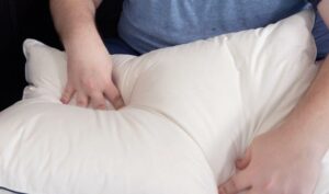 A man presses his hands into the Pacific Coast Feathers down pillow.