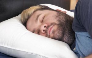 A man sleeps on his side using the Parachute Homes down pillow