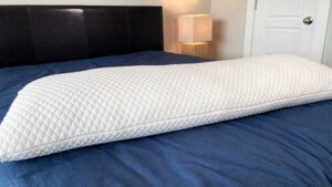 An image of the Pluto Puff body pillow on a bed.