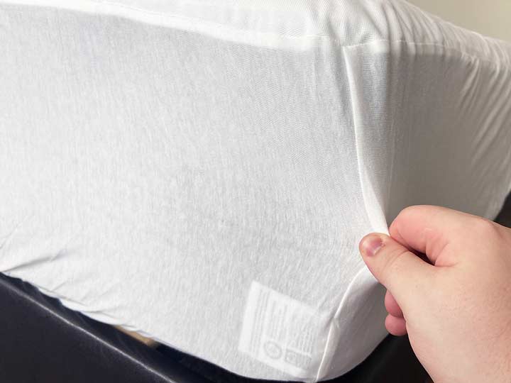 A hand pulls the side of the Saatva Mattress protector.