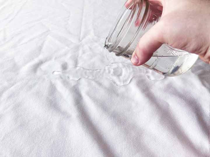 A man pours water on the Saatva mattress protector to demonstrate its ability to repel water.