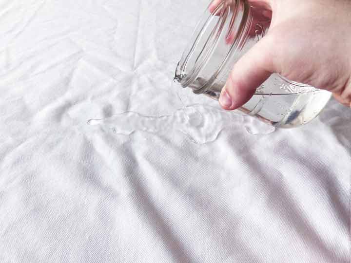 man pouring water onto Saatva mattress protector