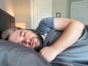 A man sleeps on his side with the Pizuna Sheets.