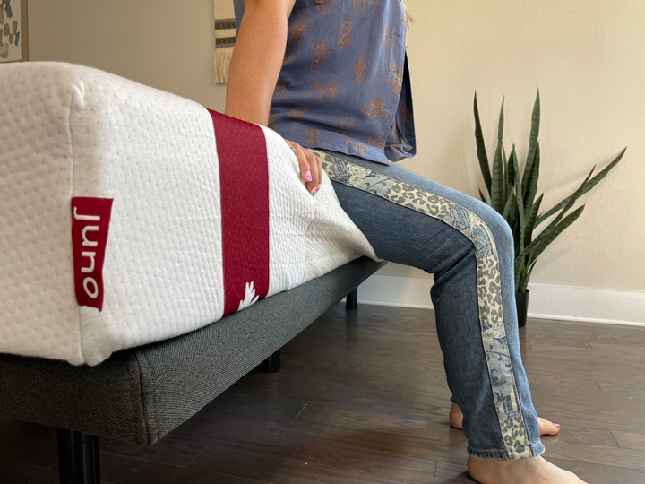 A woman sits on the edge of the Juno mattress