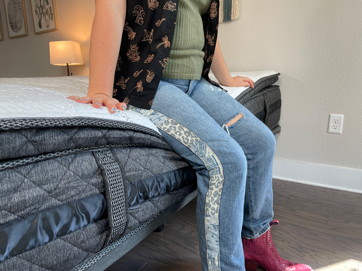 A woman sits on the edge of the Logan and Cove mattress