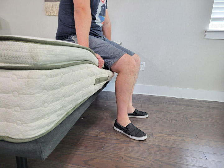 A man sits near the edge of the Avocado Green mattress