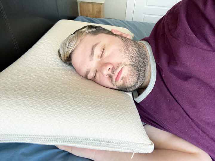 A man sleeps on his side with the Avocado Molded Latex Pillow