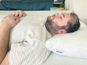 A man Sleeps on his back with the Purple Cloud Pillow.