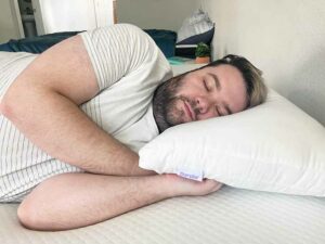 A man sleeps on his side with the Purple Cloud Pillow.