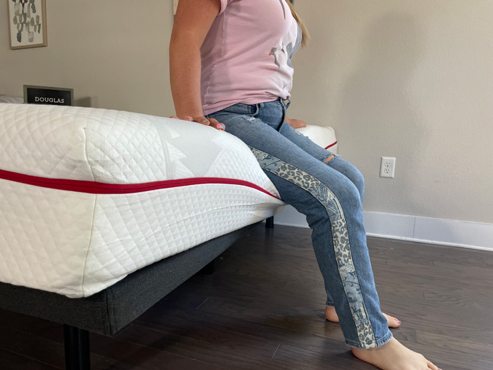 A woman sits on the edge of the Douglas mattress