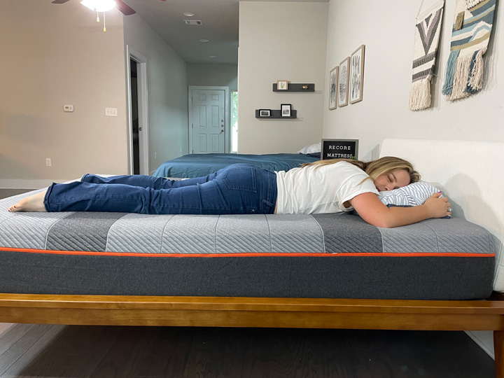 A woman rests on her stomach on the Recore mattress