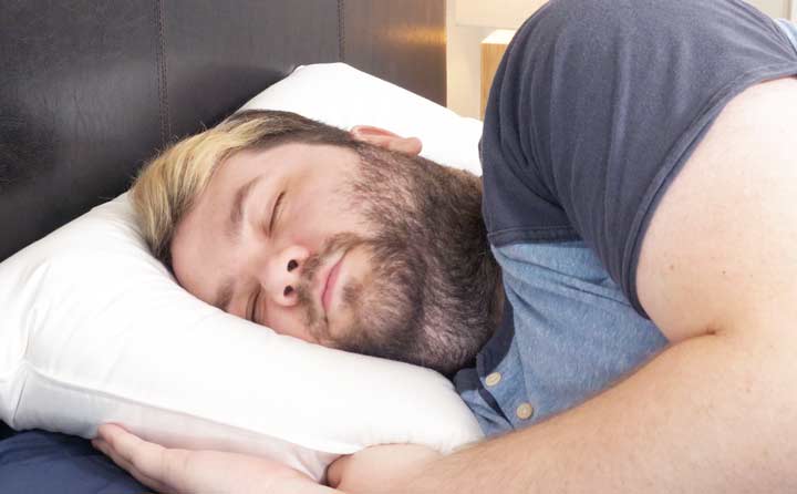 A man sleeps on his side with the Helix Down & Feather Pillow.