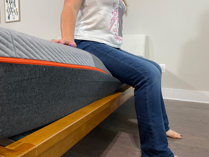 A woman sits on the edge of the Recore mattress.