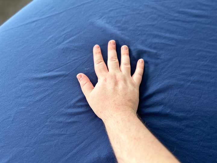 A hand brushes across the navy Sweave Eucalyptus sheets.