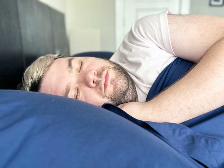 A man sleeps on his side using the Sweave Eucalyptus sheets.