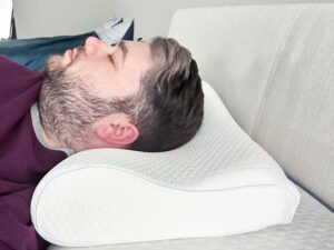 A man rests on his back using the TEMPUR-Neck Pillow.