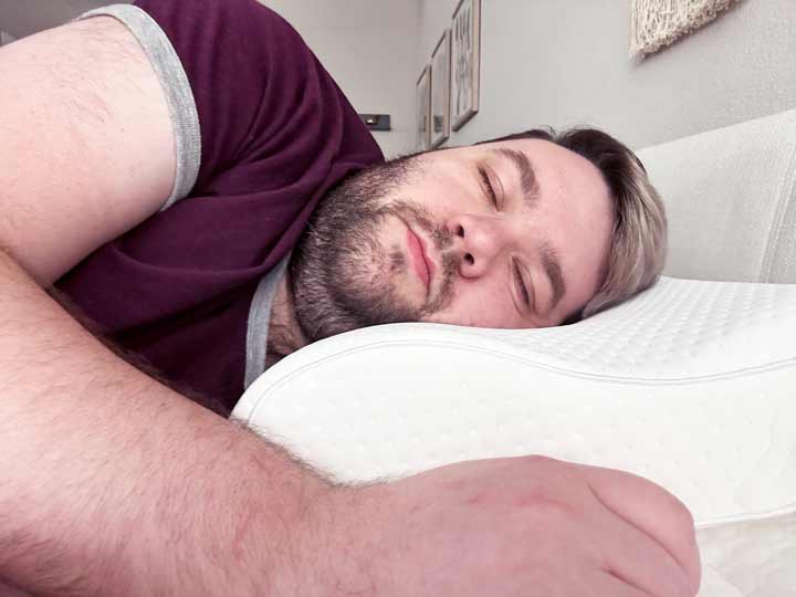 A man sleeps on his side using the TEMPUR-Neck pillow