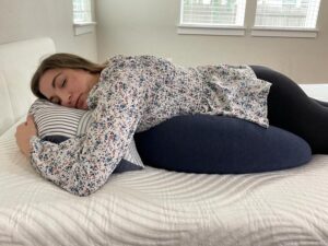 A woman rests with the BBHugMe Pillow