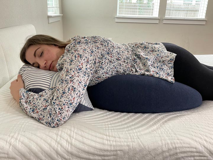 a woman sleeps with the BBHugMe pregnancy pillow