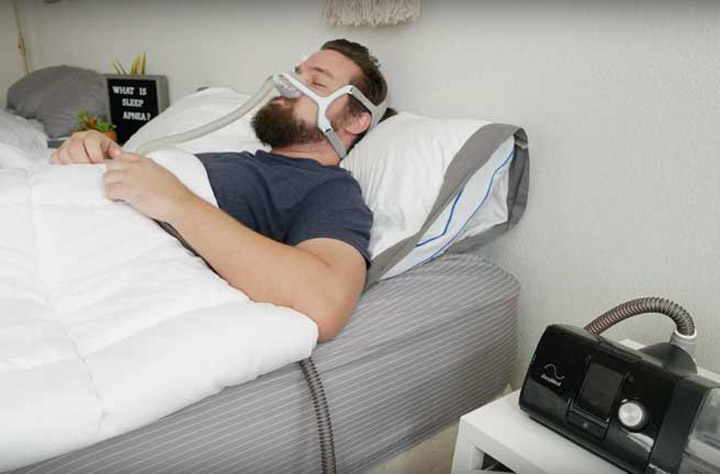 A man sleeps on his back with a CPAP machine on his face.