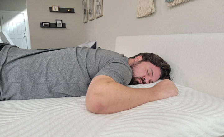 A man sleeps on his stomach on the Minocasa Hybrid mattress.