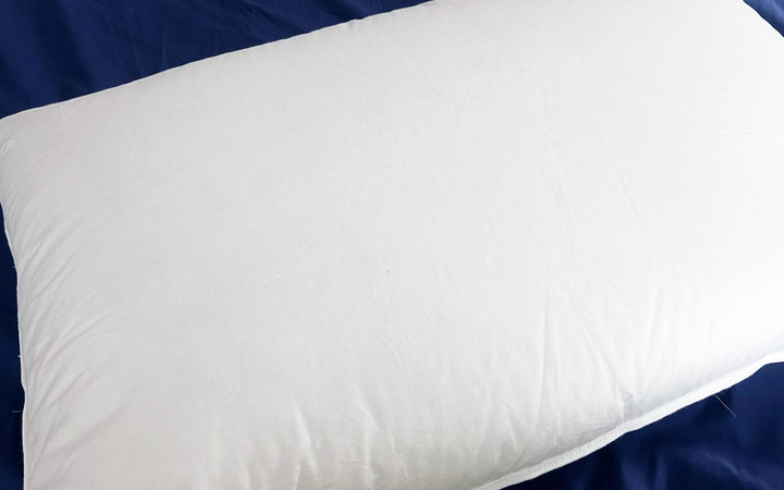 A picture of the white cotton cover of the Plushbeds Goose Down Pillow.