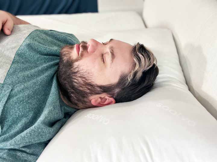 An image of a man sleeping on his back using the Saatva Down Alternative Pillow.