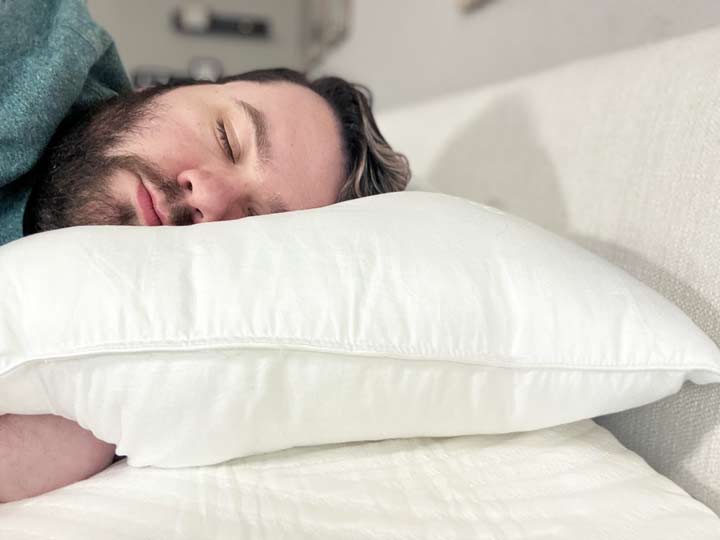 A man sleeps on his side using the Saatva Down Alternative Pillow.