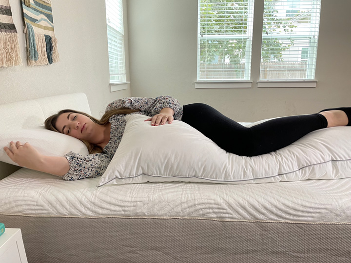 A woman sleeps on her side with the Tuft & Needle body pillow