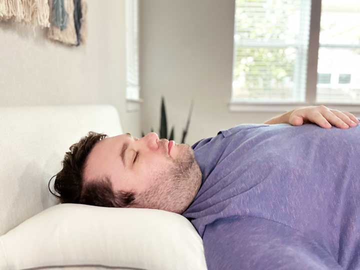 A man sleeps on his back using the Tuft & Needle Down pillow.