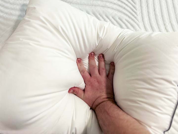 A hand makes an indentation in the Tuft & Needle Down pillow.