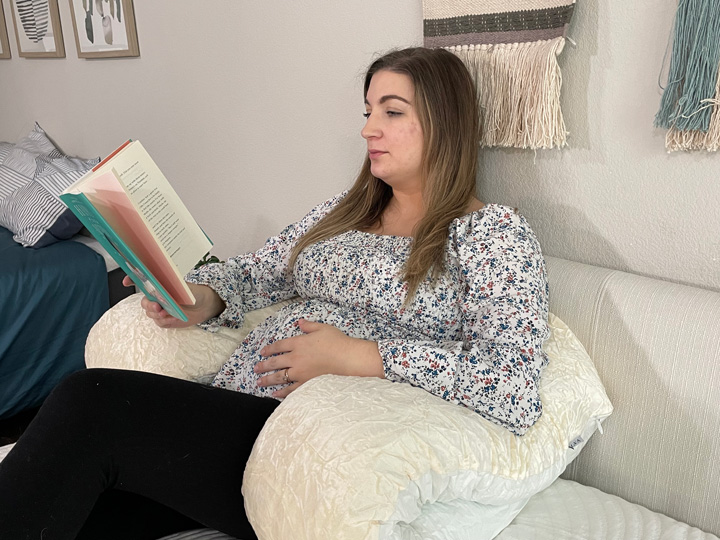 A woman lounges with the Yana 360 body pillow