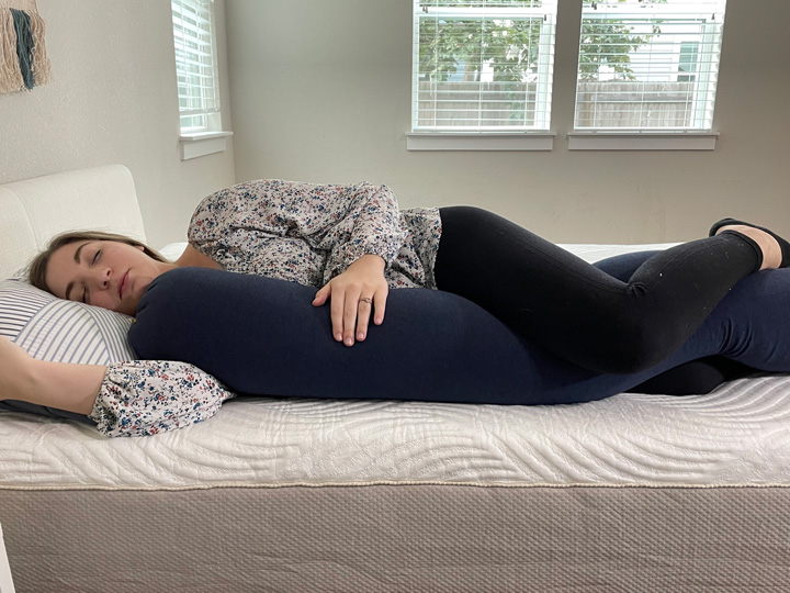 A woman sleeps on her side with the BBHugMe pillow