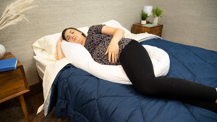 A pregnant woman sleeps on the Buffy Wiggle pillow