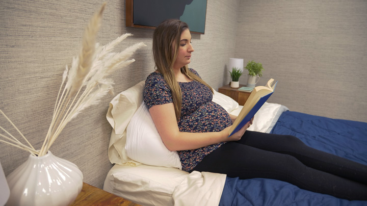 A pregnant woman lounges with the Buffy Wiggle pillow