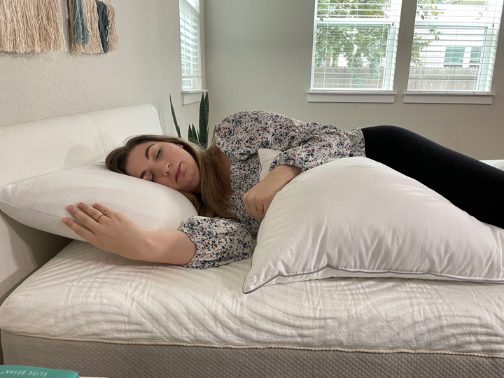 A woman sleeps on her side with the Tuft & Needle body pillow