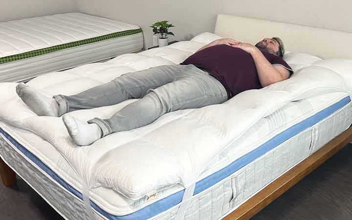 An image of a man sleeping on his back while on top of the Coop Home Goods Retreat Mattress Topper.