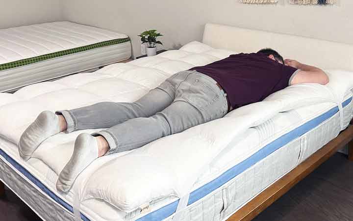A man sleeps on his stomach with the Coop Home Goods Retreat Mattress Topper.