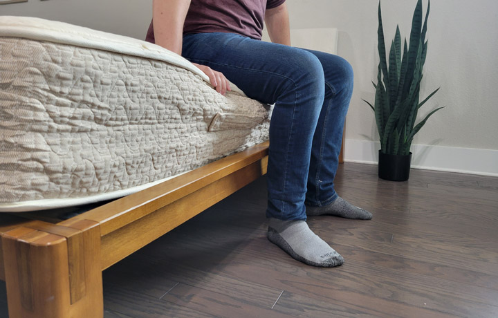 A man sits near the edge of the Lytton Signature mattress