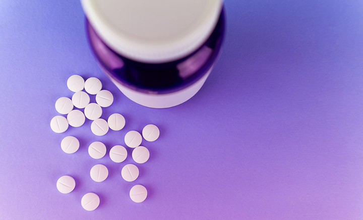 A close shot of a pill bottle with pills next to it