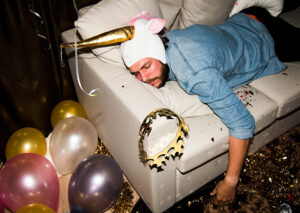 A man sleeps on a couch covered in New Year's regalia