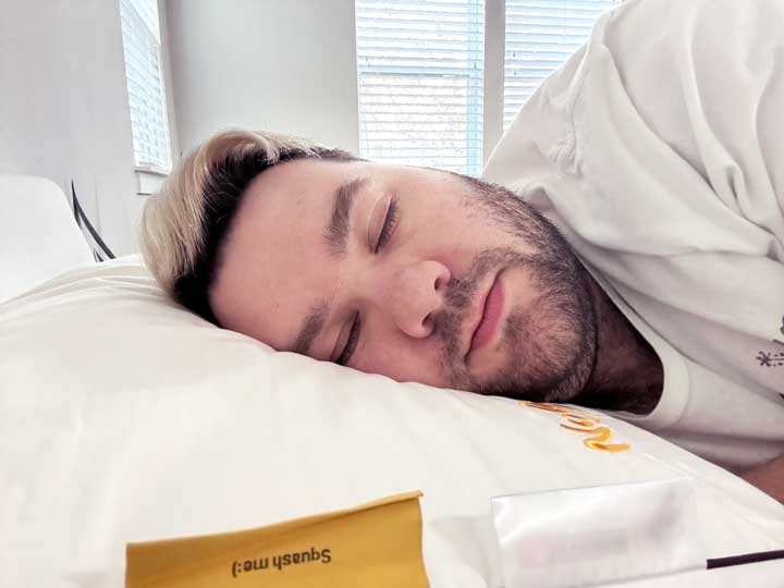 An image of a man facing the camera, sleeping on his side using the Nolah Cooling Foam pillow.