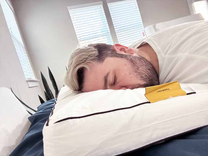 An image of a man sleeping on his stomach while using the Nolah Cooling Foam pillow.