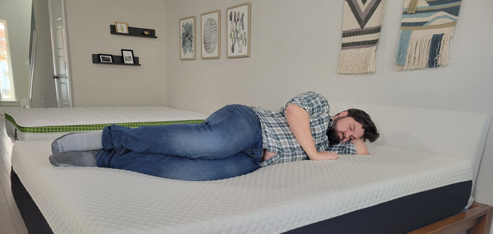 A man sleeps on his side on the Nolah Signature Hybrid mattress.