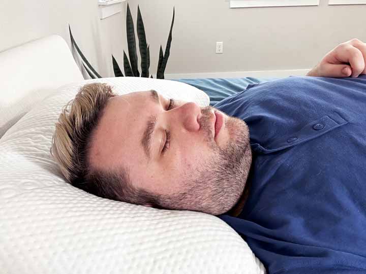 A man rests on his back using the Saatva Memory Foam Pillow.