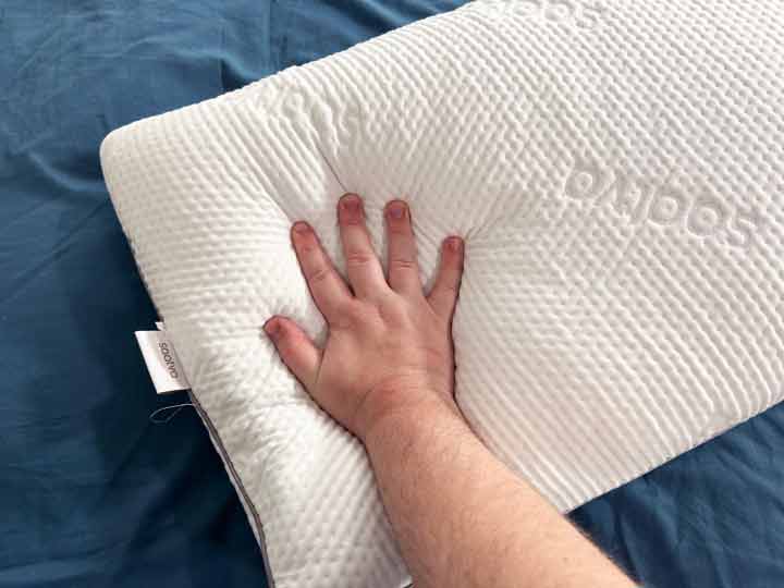 A man presses his hand into the saatva memory foam pillow.