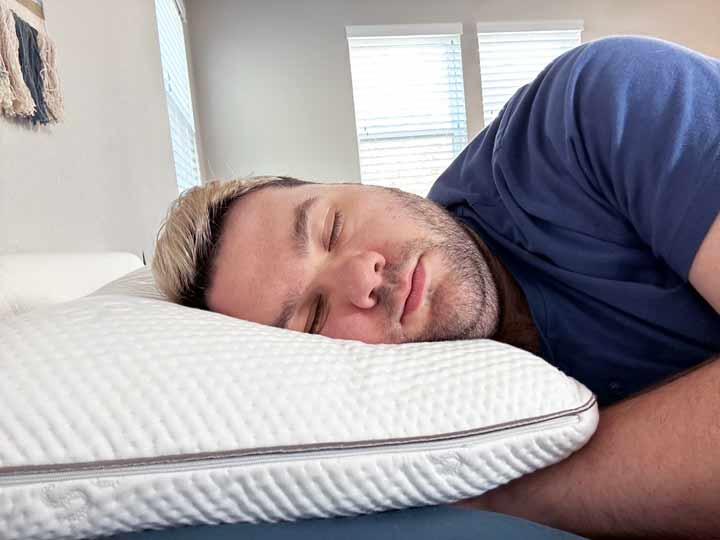 A man rests on his side using the Saatva Memory Foam Pillow.