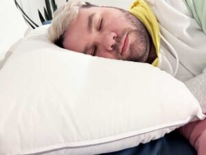 An image of a man resting on his side using the Tuft & Needle Down Alternative pillow.